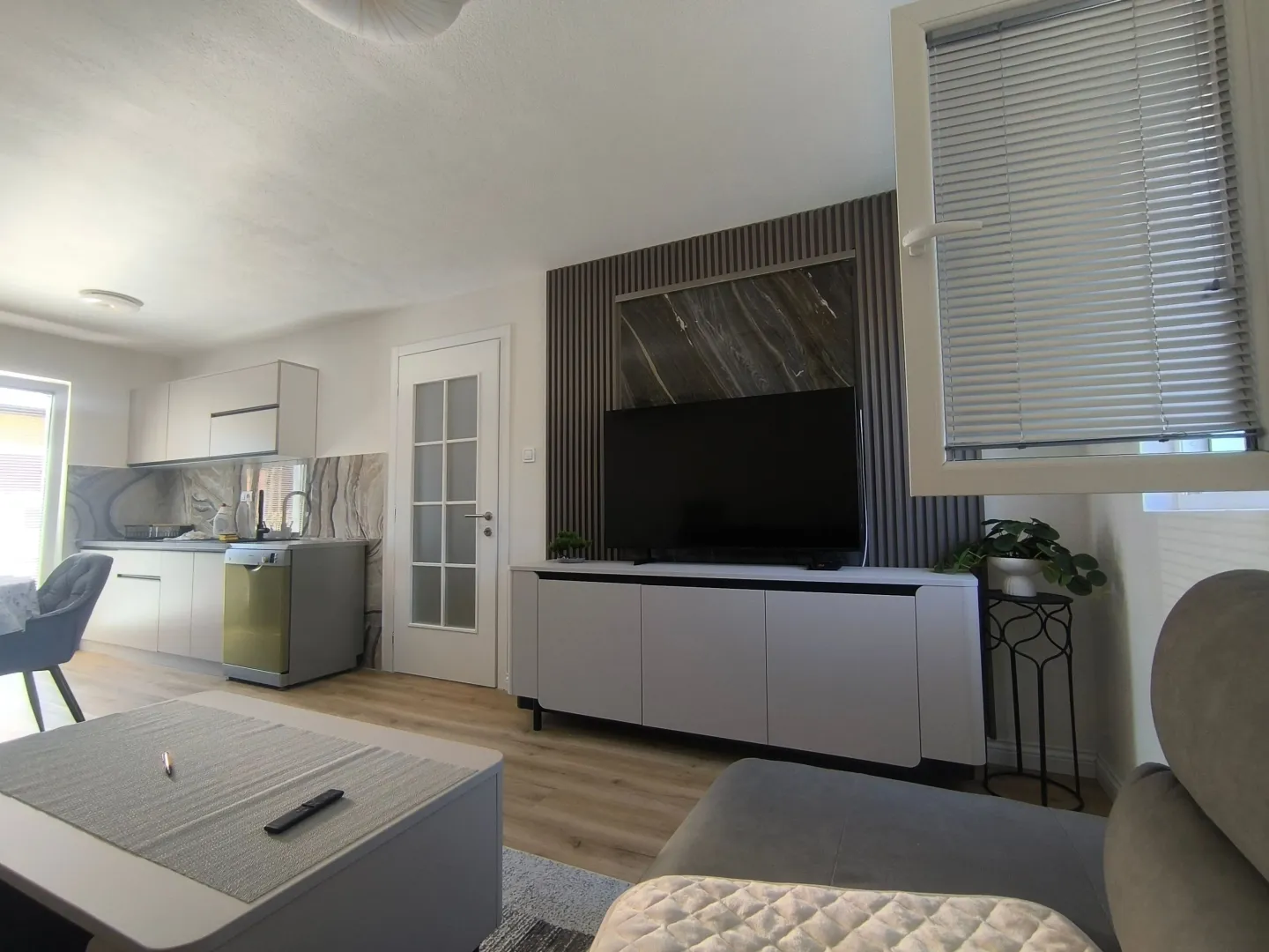Living room with sofa, TV unit, and a view of the kitchen.