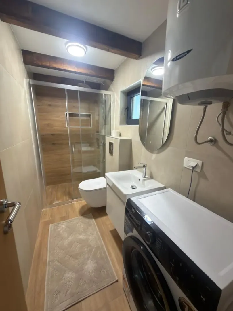 Modernly equipped bathroom with a walk-in shower, washbasin, and washing machine.