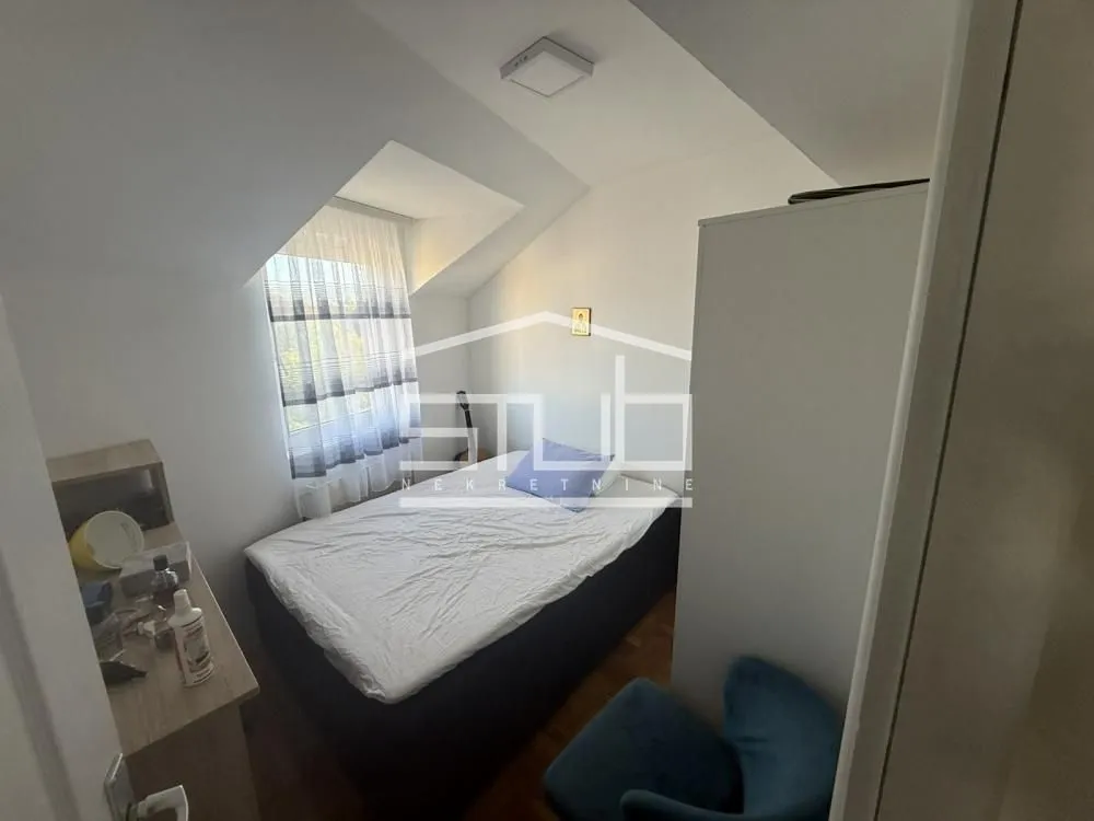 Smaller bedroom with a bed and a slanted roof window in the attic.