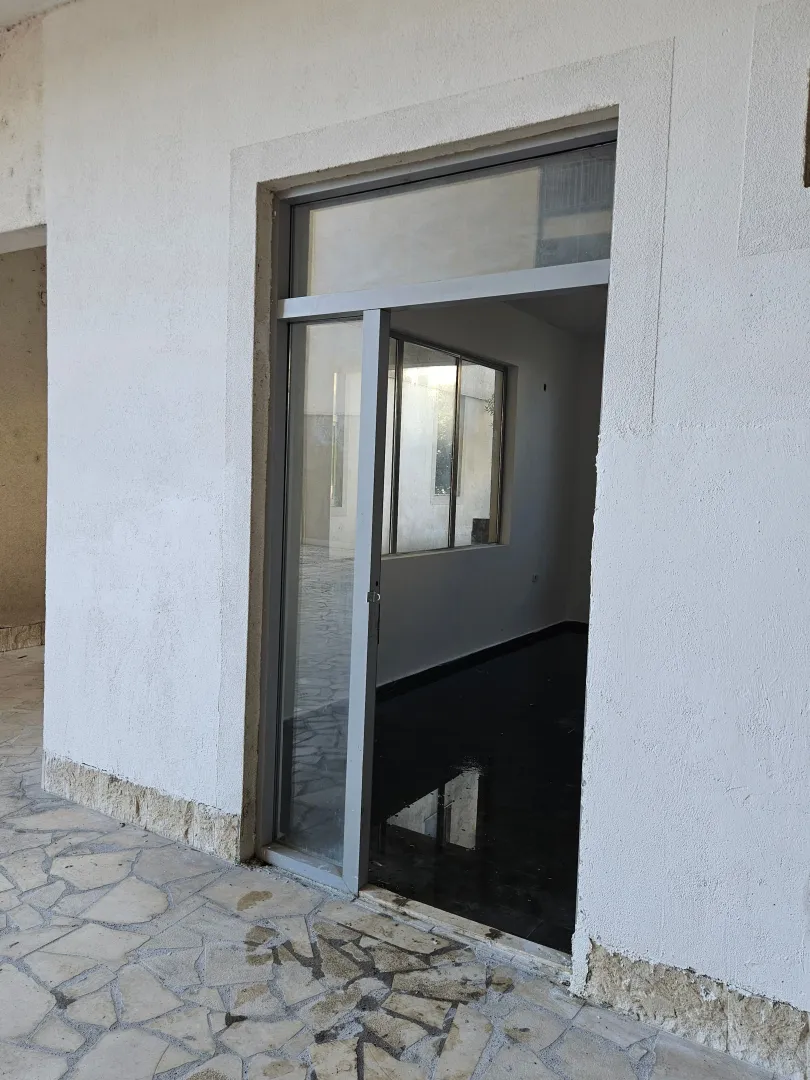 Entrance to a commercial space with glass doors and a paved courtyard.