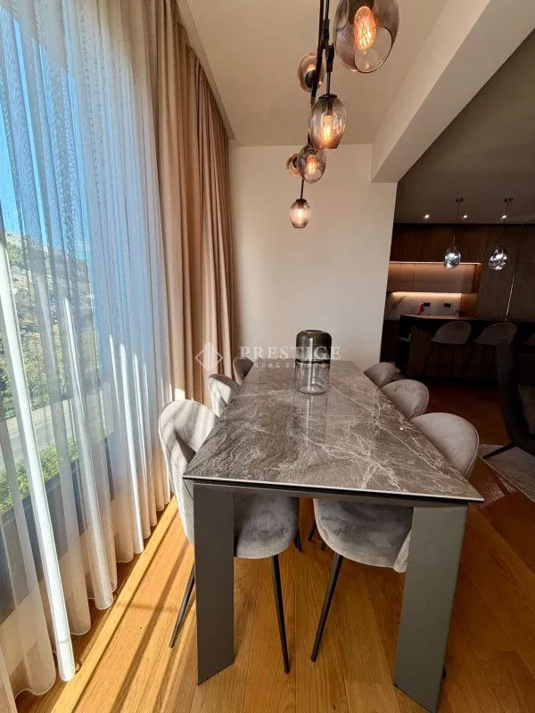 Dining area with a modern table and chairs next to a large window.