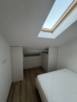Attic bedroom with a bed, fitted wardrobes, and a skylight. - image 10