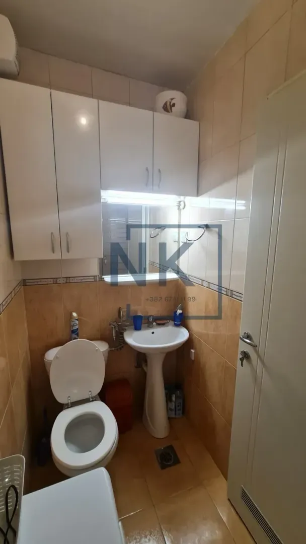 Smaller bathroom with sanitary ware, washbasin, mirror and white wall-mounted cabinet.