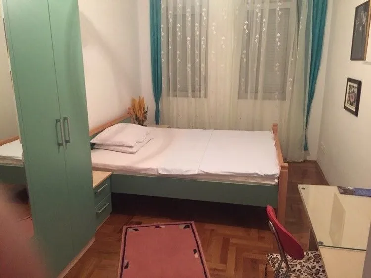 Jednostavna spavaća soba sa zelenim ormarom i drvenim krevetom.