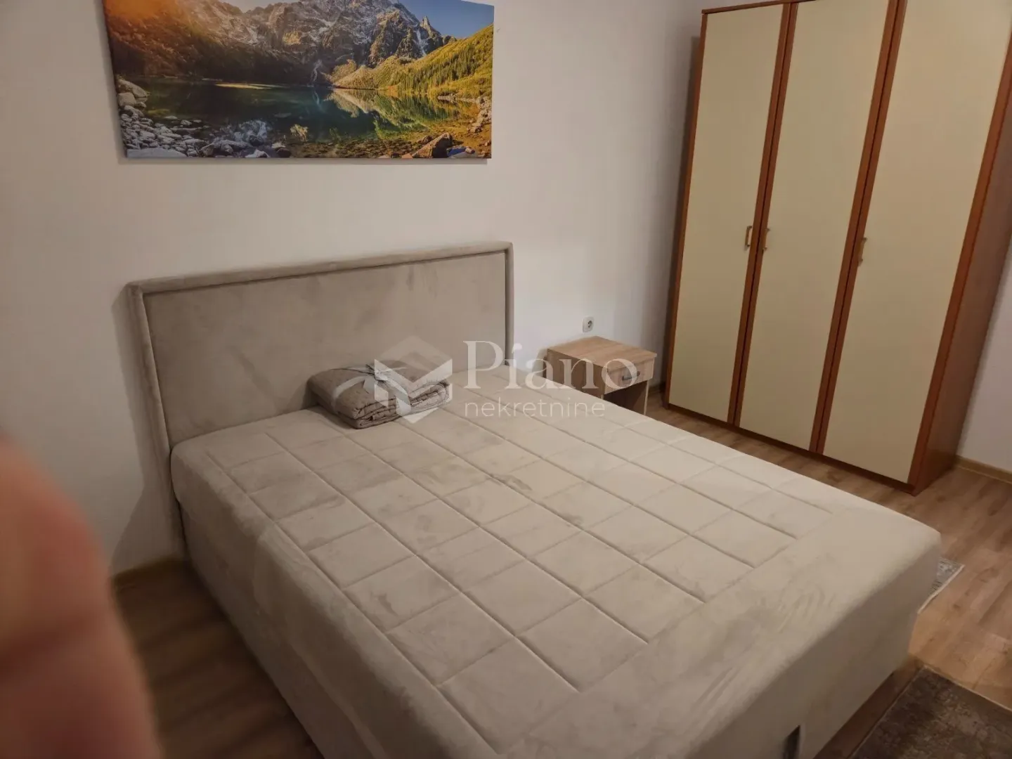 Spavaća soba sa bračnim krevetom, noćnim stočićem i plakarom.