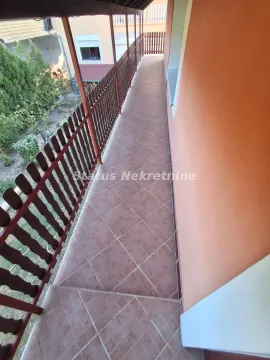 Long covered balcony with tiled flooring and a wooden railing. - image 9