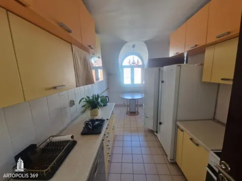 Dugačka kuhinja sa žutim elementima i trpezarijskim stolom kod prozora. - image 4