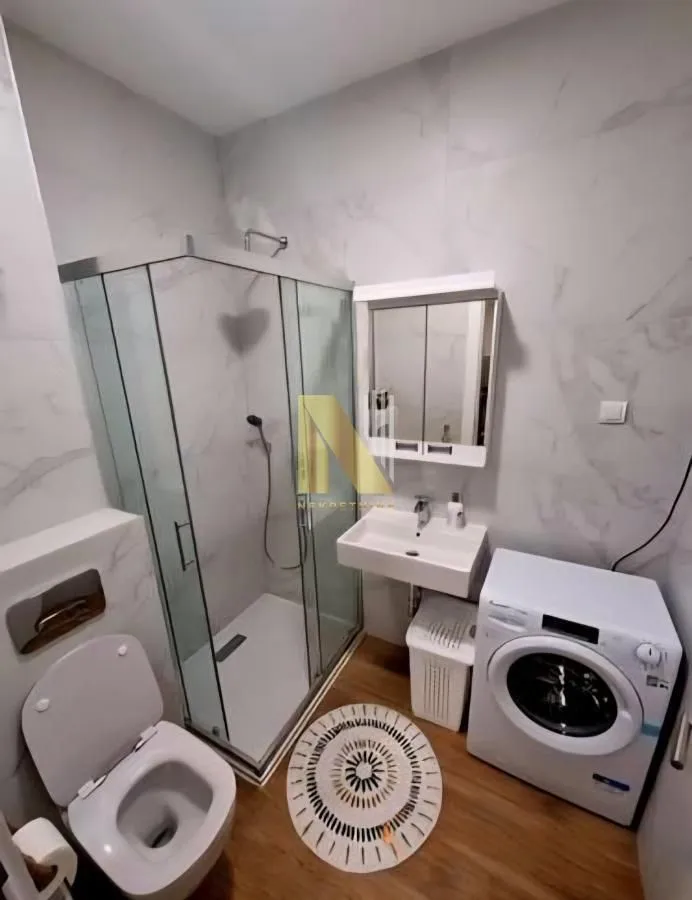 Moderno kupatilo sa tuš kabinom, umivaonikom, wc šoljom i veš mašinom.