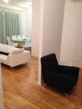 Svijetla dnevna soba sa bijelim kaučem, crnom foteljom i trpezarijom u pozadini. - image 8