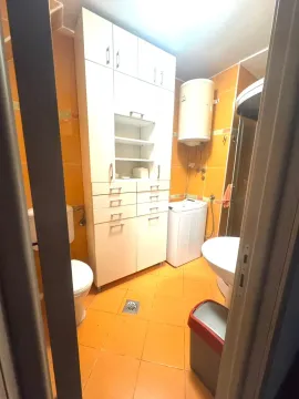 Manje kupatilo sa narandžastim pločicama, bijelim elementima, veš mašinom i bojlerom. - image 8