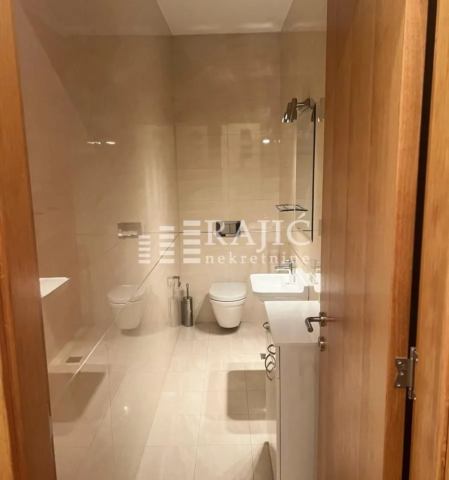 View of a modern bathroom with sanitary fixtures through an open door.