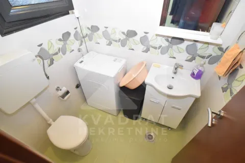 Small bathroom with a toilet, washbasin, and washing machine. - image 14