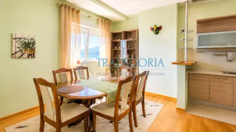 Trpezarija sa drvenim stolom i stolicama, povezana sa kuhinjom i pogledom na more. - image 3