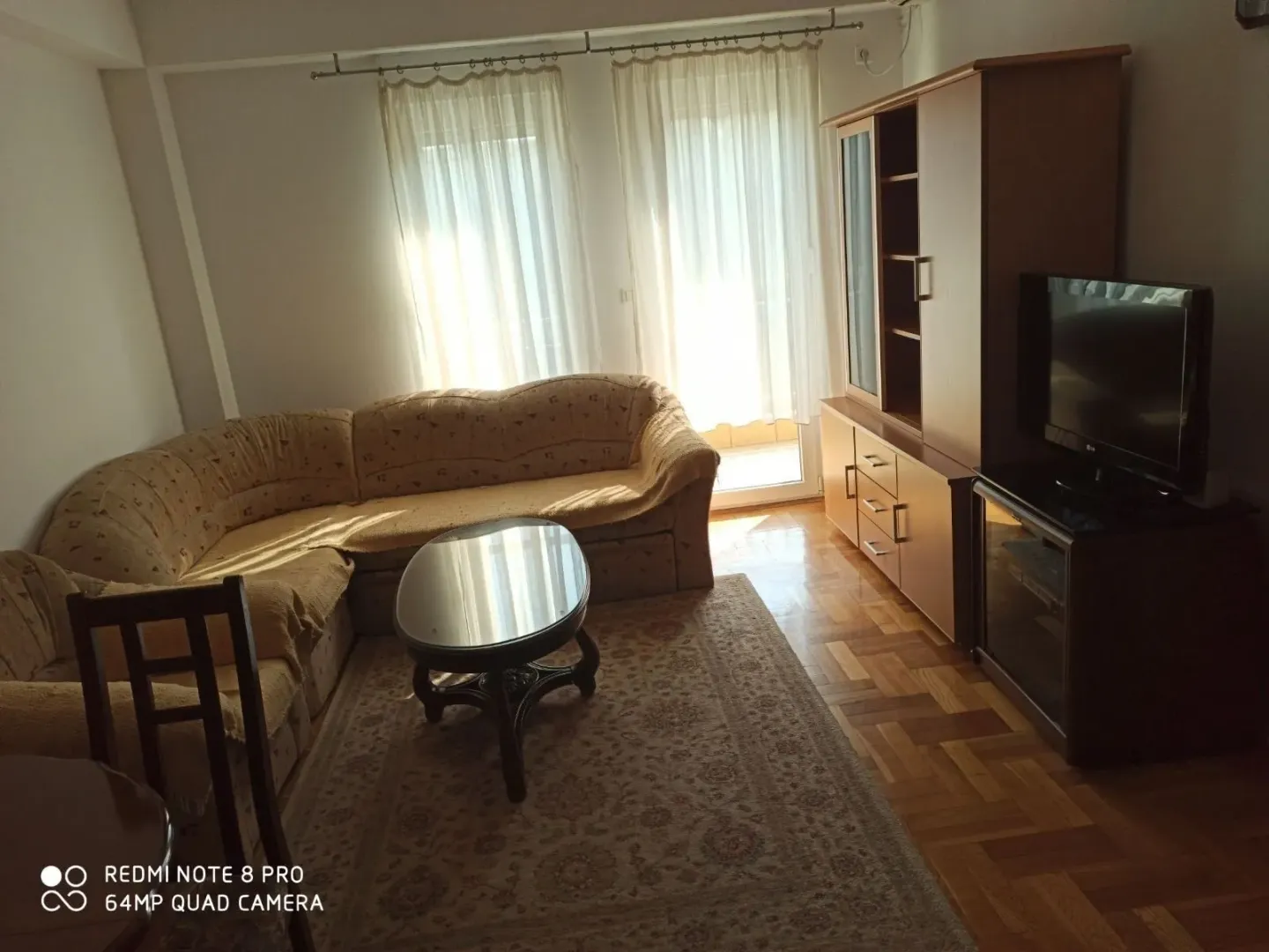 Svijetla dnevna soba sa ugaonom garniturom i televizorom.