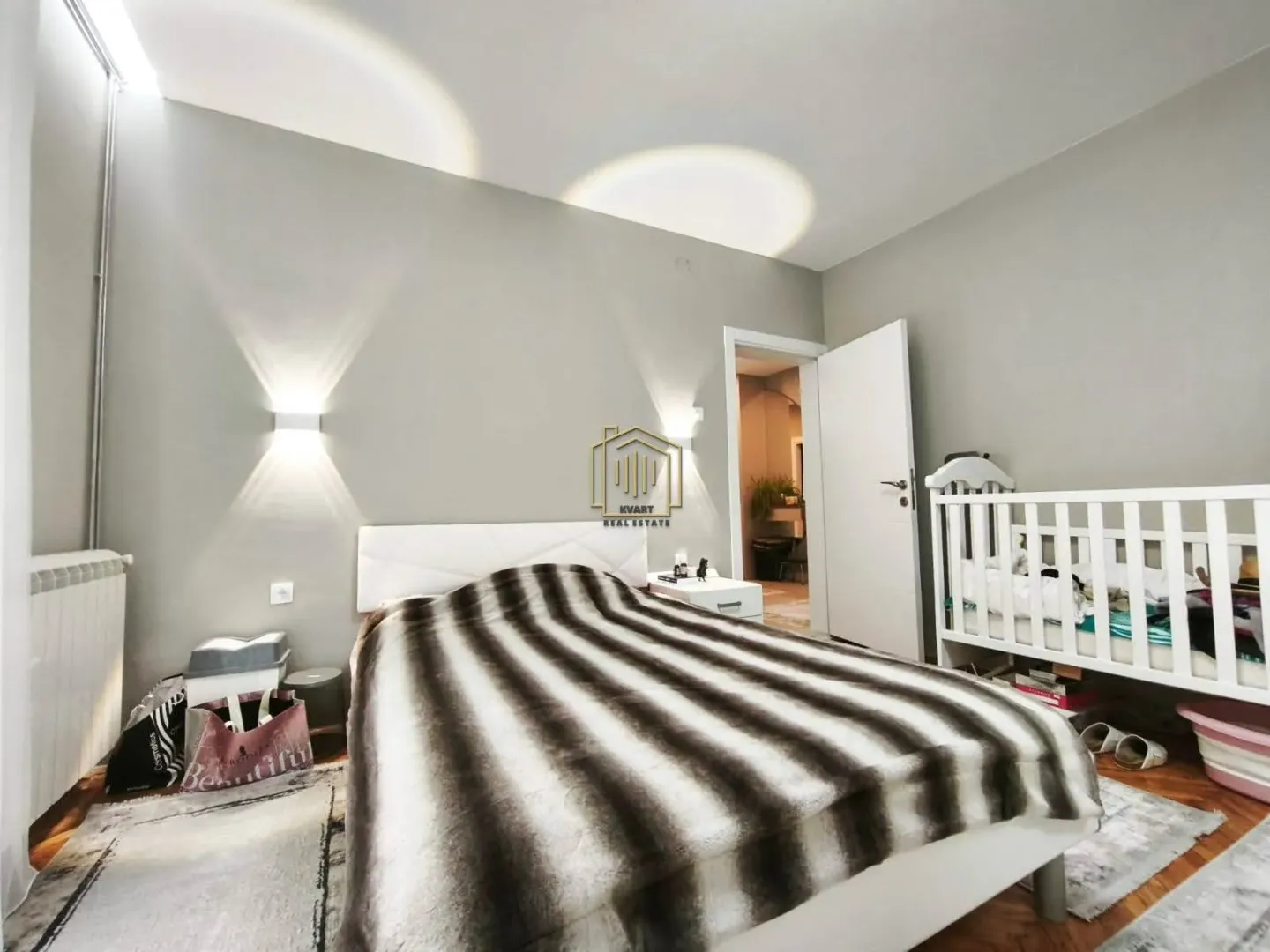 Furnished bedroom with a double bed and a baby crib.