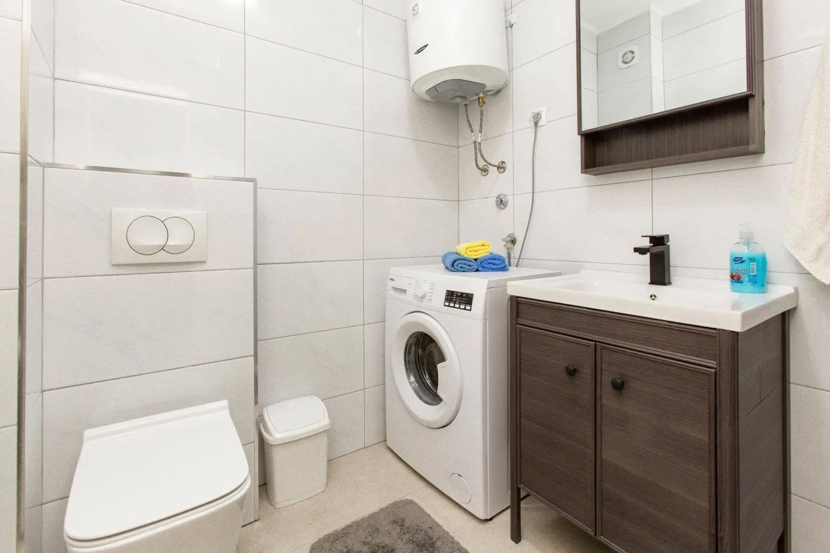 Compactly equipped bathroom with sanitary ware, washbasin, washing machine, and water heater.