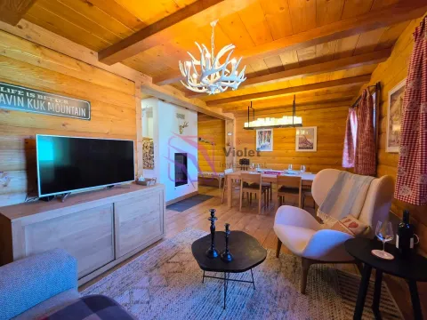 Dnevna soba u drvenoj vikendici sa televizorom, garniturom za sjedenje i trpezarijom u pozadini. - image 7