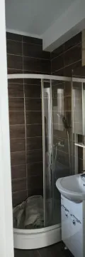Manje kupatilo sa tuš kabinom i umivaonikom obloženo tamnim pločicama. - image 14
