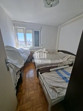 Spavaća soba sa krevetima i prozorom sa pogledom na grad. - image 6