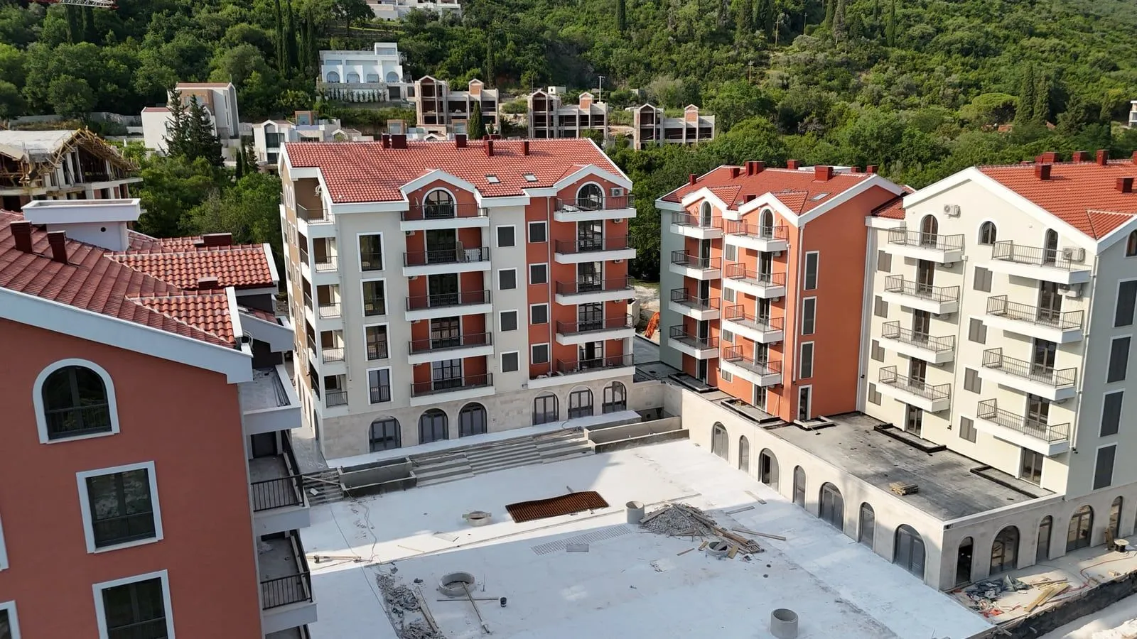 Pogled odozgo na novoizgrađeni stambeni kompleks sa crvenim krovovima.