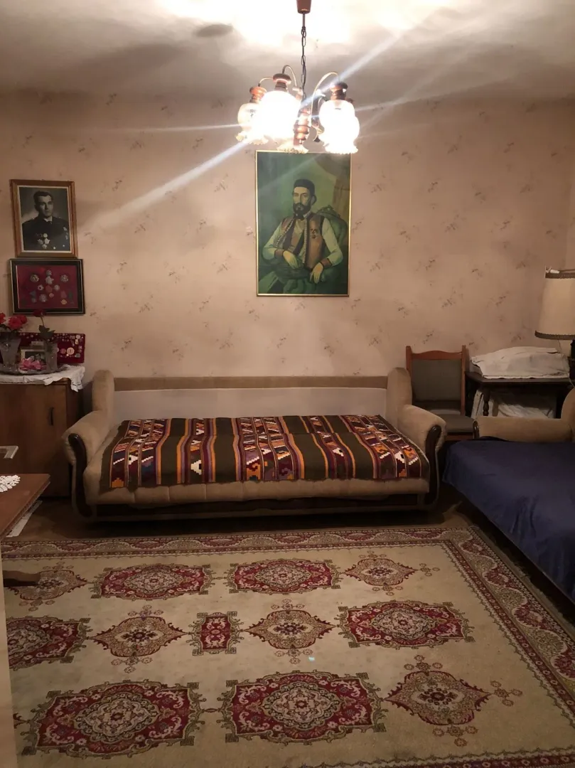 Dnevna soba sa klasičnim namještajem, tepihom i slikama na zidu.