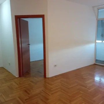Empty room with parquet flooring, white walls, and an open wooden door. - image 11