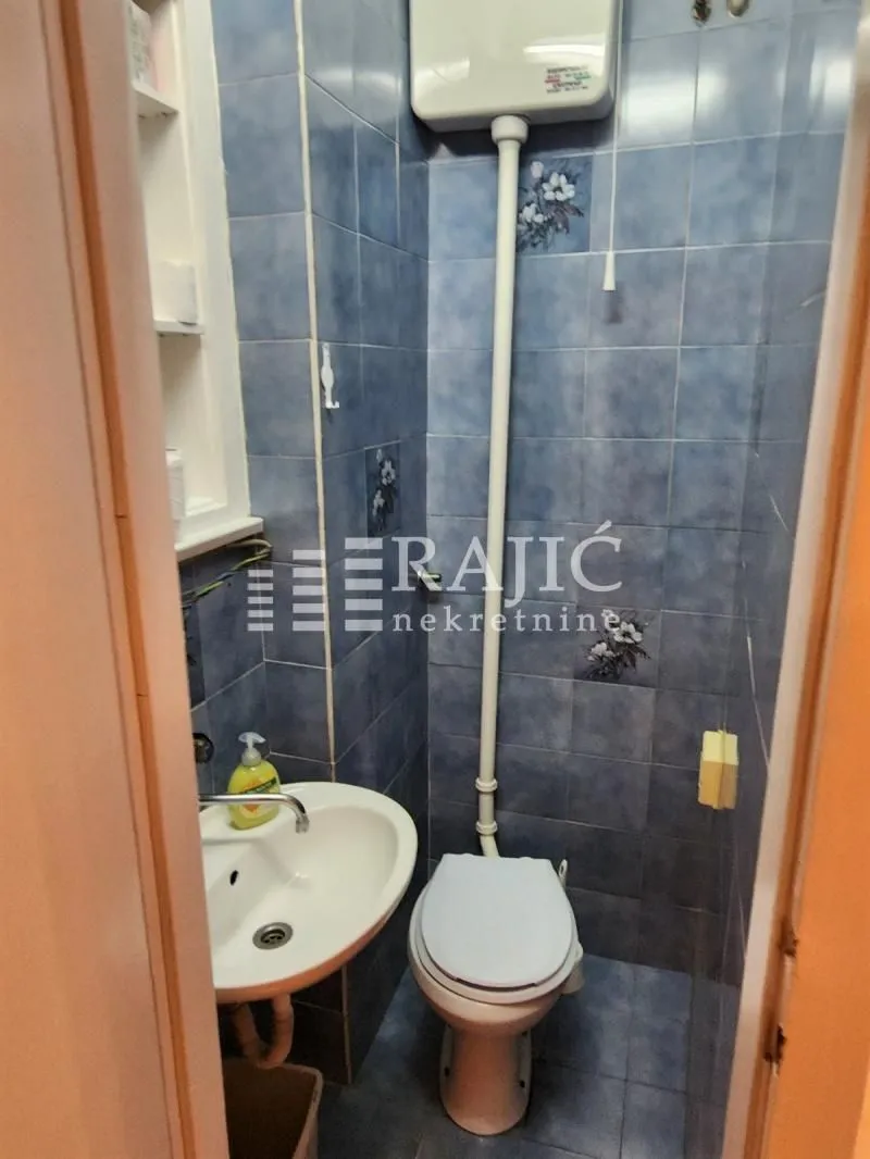 Small bathroom with blue tiles, washbasin, and toilet.
