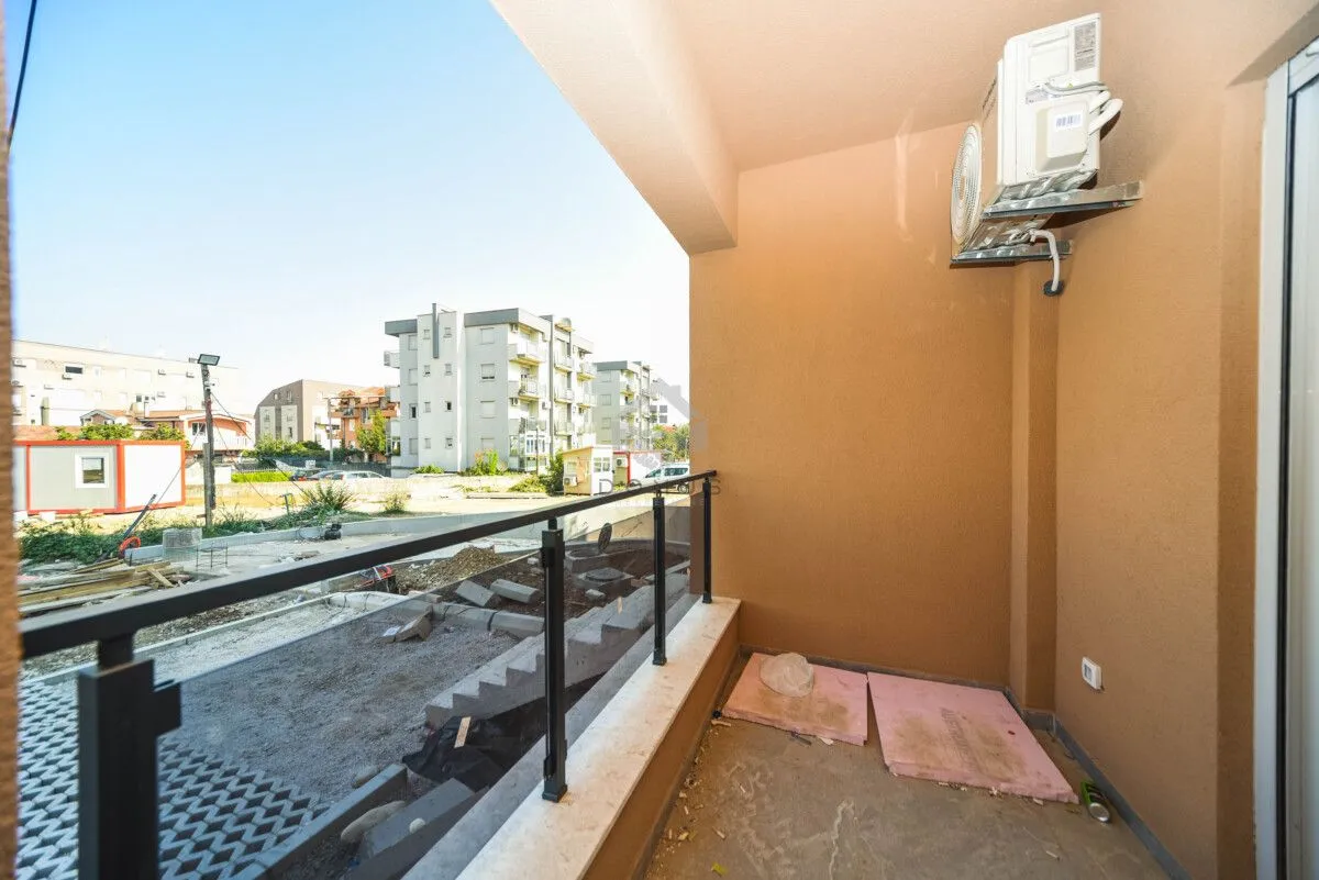 Manji natkriveni balkon sa metalnom ogradom i klima uređajem.