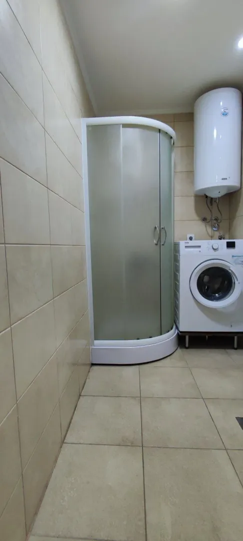 Simple bathroom with a shower cabin and washing machine.