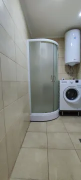 Simple bathroom with a shower cabin and washing machine. - image 10