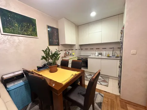 Trpezarija sa drvenim stolom i kuhinja u pozadini. - image 3