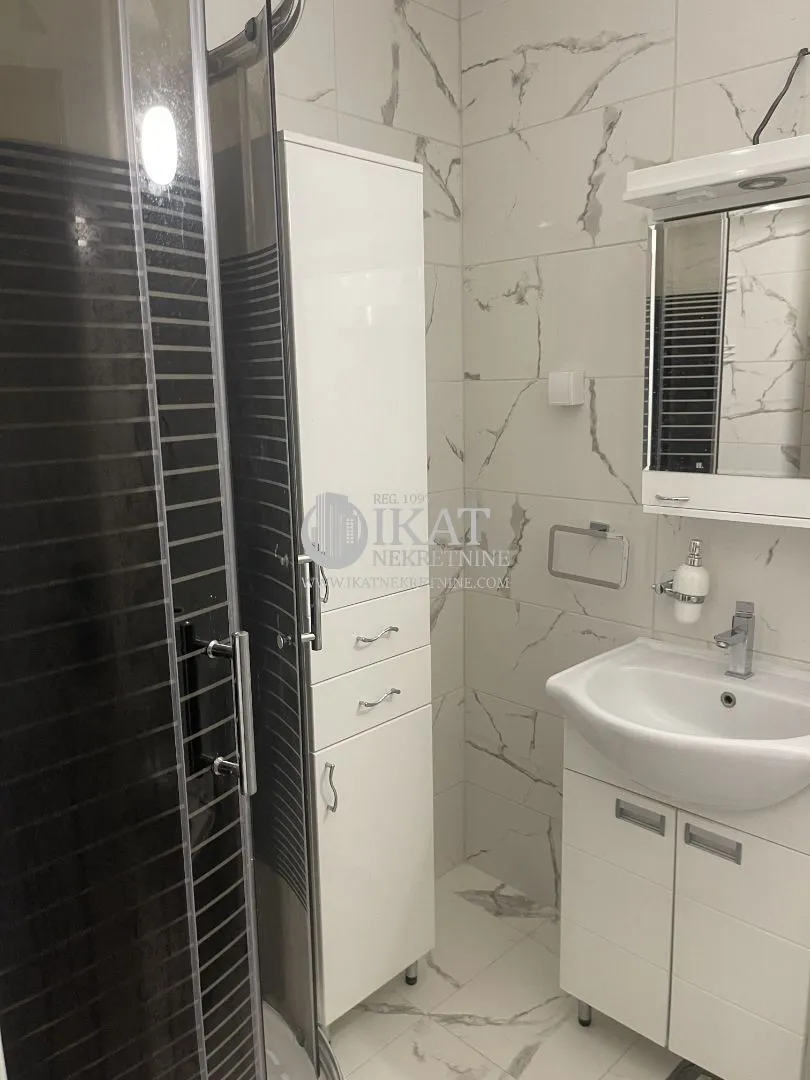 Modern bathroom with a shower cabin, washbasin, and white cabinetry.