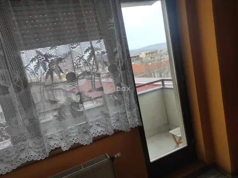 Pogled kroz prozor sa čipkanom zavesom na terasu i okolne zgrade. - image 5