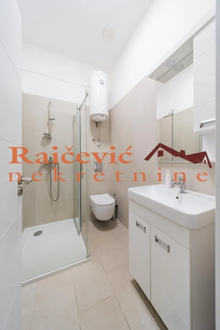 Savremeno opremljeno kupatilo sa tuš kabinom, umivaonikom i wc šoljom.