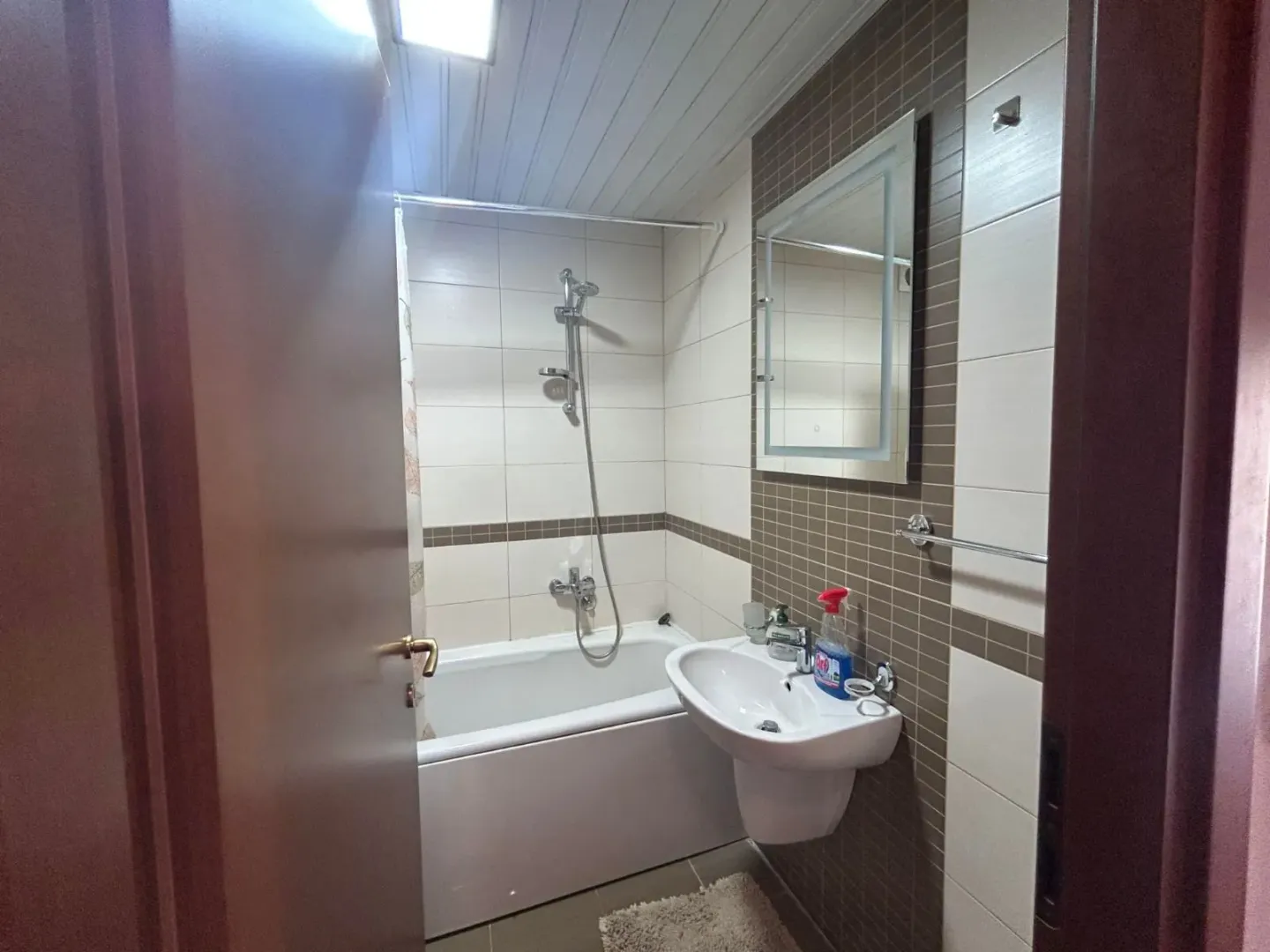 View of the bathroom with a bathtub, sink, and mirror.