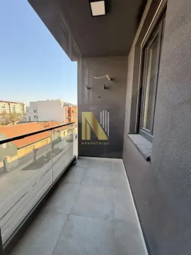 Moderna popločana terasa sa staklenom ogradom i pogledom na grad. - image 13
