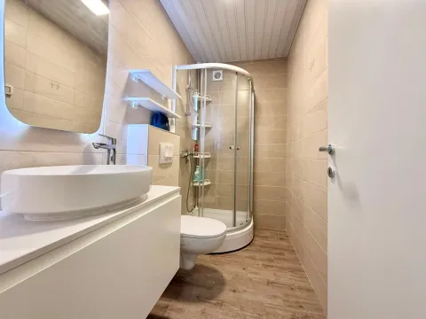Manje kupatilo sa umivaonikom, tuš kabinom i toaletom u bež tonovima. - image 13