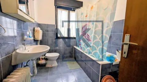 Bathroom with blue tiles, washbasin, toilet, and bathtub with a curtain. - image 14