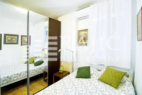 Furnished bedroom with a large double bed and a mirrored wardrobe.