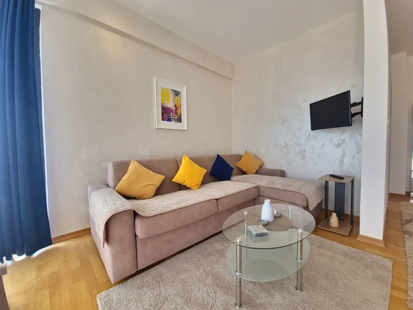 Living room with a sectional sofa, coffee table, and wall-mounted TV.