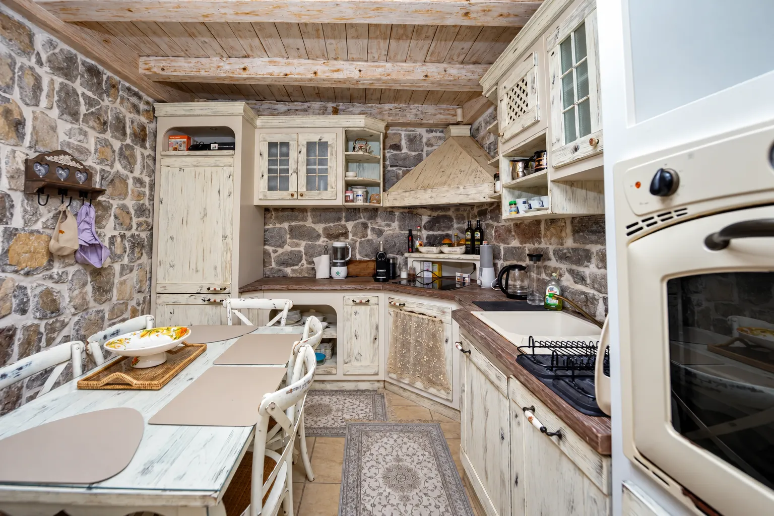 Rustic kitchen with a dining table and exposed stone walls.