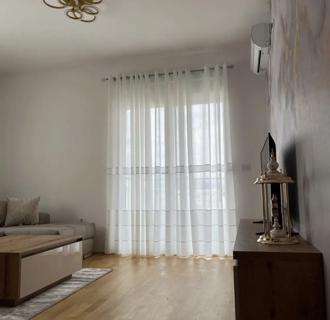 Svijetla dnevna soba sa drvenim stolom i bijelim zavjesama.