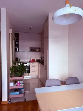Small kitchen with light-colored cabinetry and a dining table in the foreground. - image 2