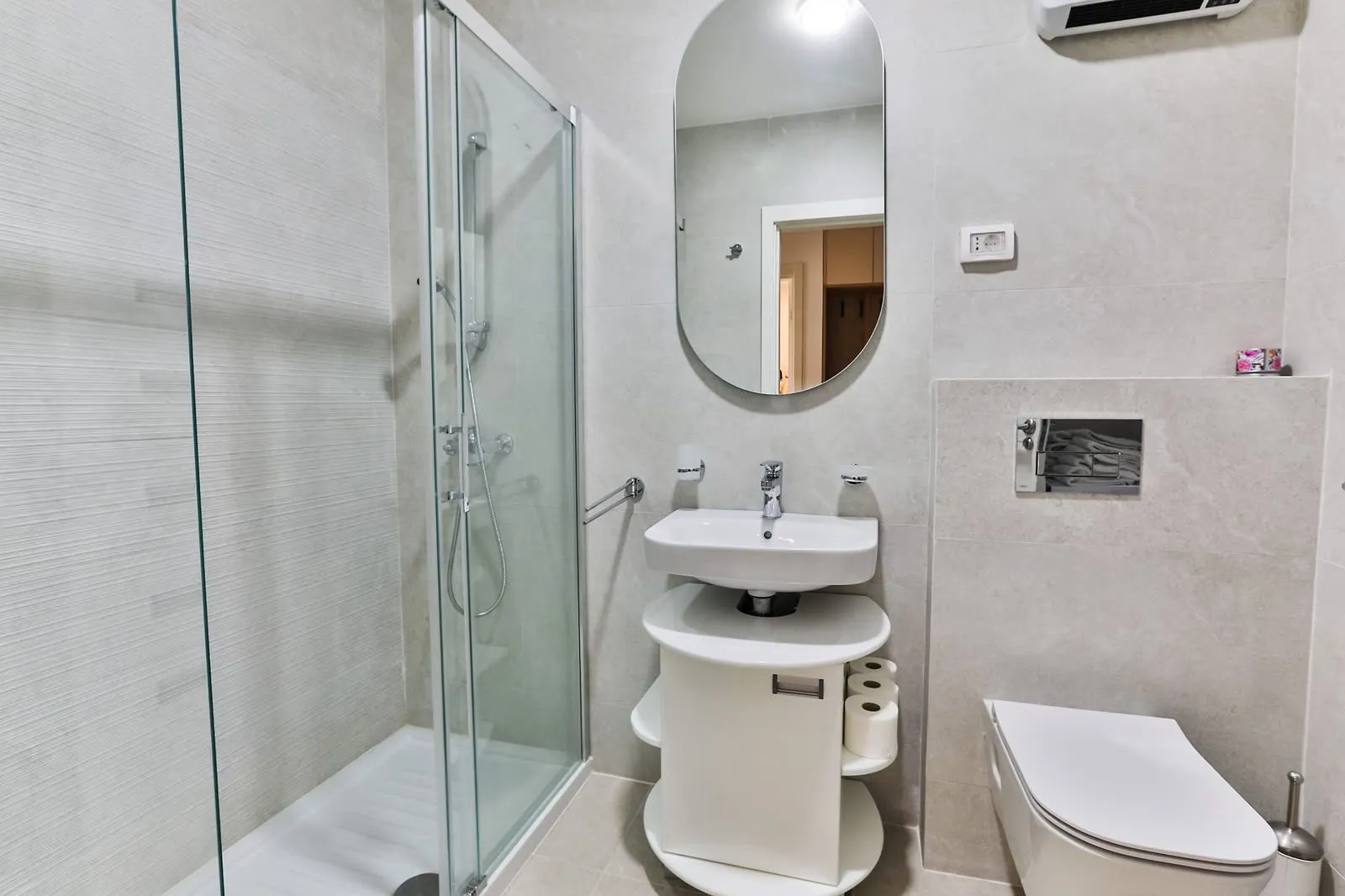 Modernly equipped bathroom with a walk-in shower, washbasin, and toilet.