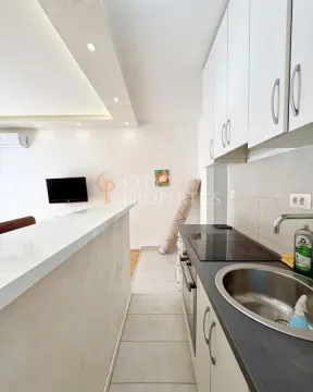 View of a smaller kitchen with white cabinetry and a breakfast bar. - image 4
