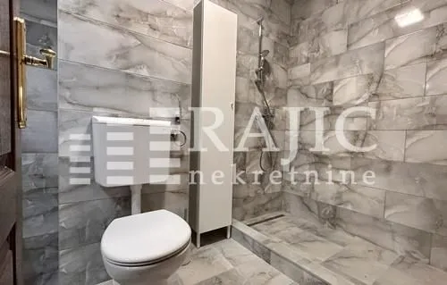 Modernly equipped bathroom with a walk-in shower and grey ceramic tiles.