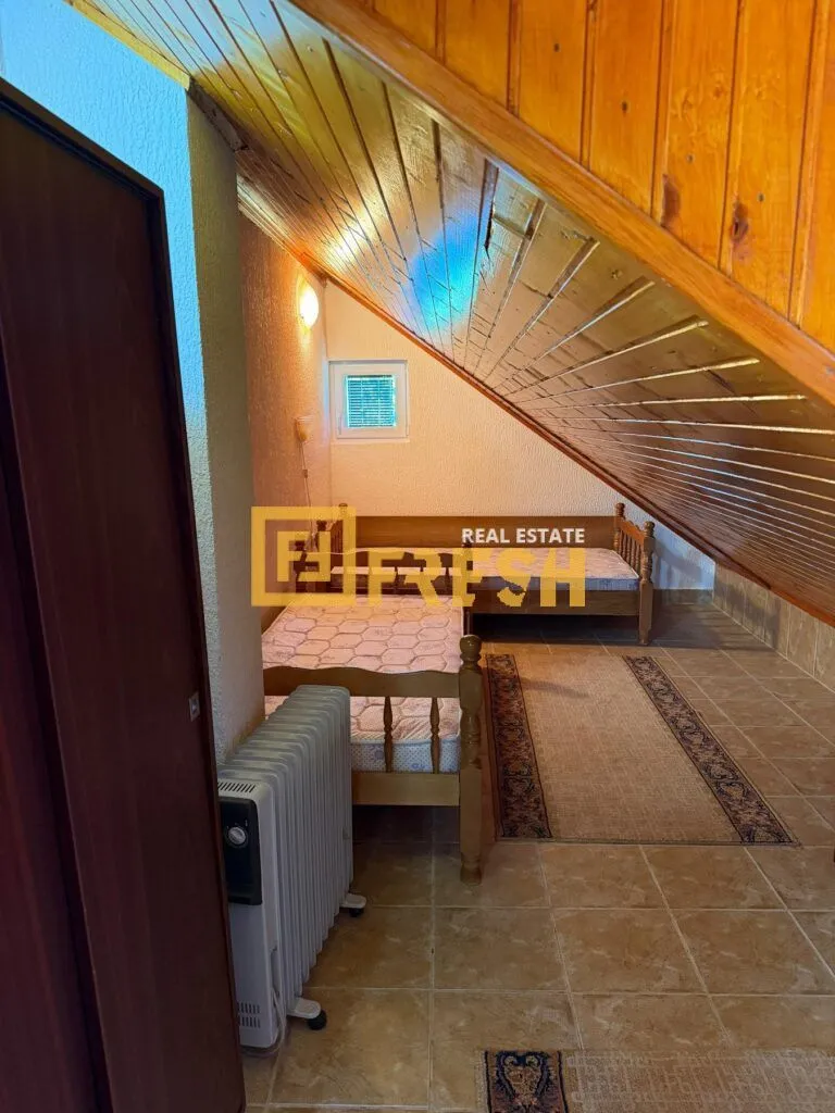 Potkrovlje sa dva drvena kreveta i kosim plafonom obloženim drvenom lambrijom.
