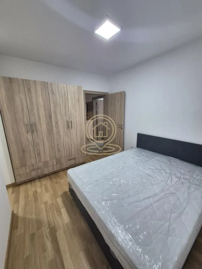 Spavaća soba sa bračnim krevetom i velikim drvenim garderoberom.