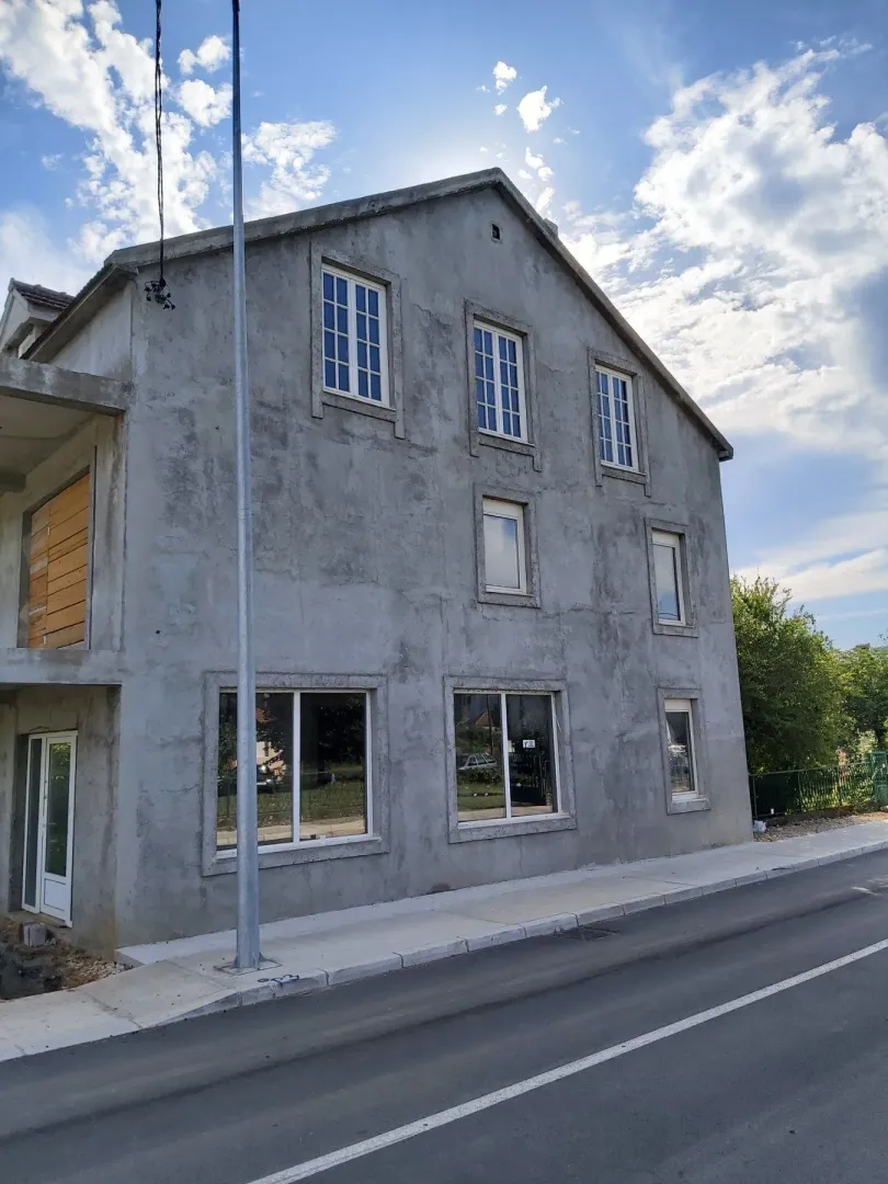 Facade of a three-story house under construction next to a paved road.