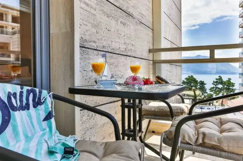 A small table and chairs set up on the balcony with a sea view. - image 9